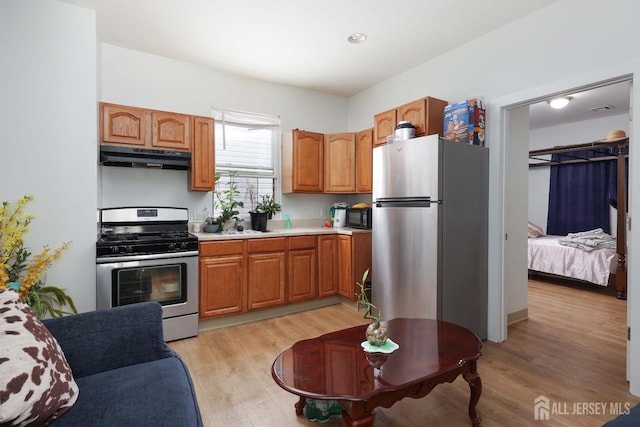 440 Bruck Ave, Perth Amboy, NJ 08861 - kitchen with appliances with stainless steel finishes, under cabinet range hood, light countertops, light wood-style flooring, and brown cabinetry
