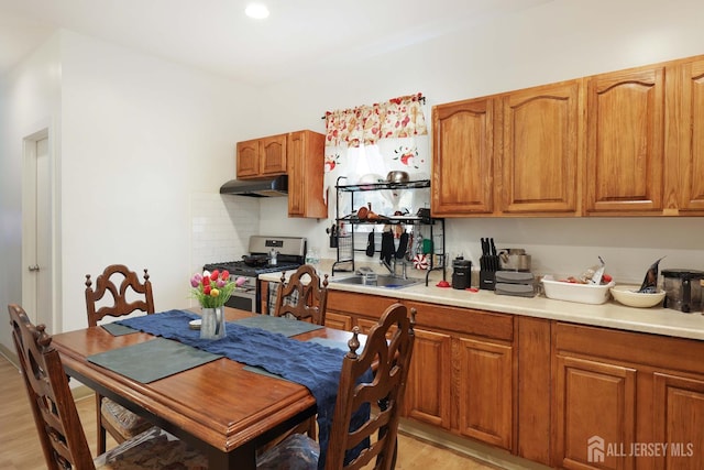 440 Bruck Ave, Perth Amboy, NJ 08861 - kitchen featuring stainless steel gas stove, under cabinet range hood, light wood finished floors, and brown cabinets
