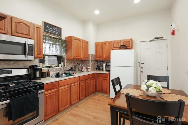 440 Bruck Ave, Perth Amboy, NJ 08861 - kitchen featuring stainless steel appliances, decorative backsplash, light wood-style floors, light countertops, and brown cabinetry