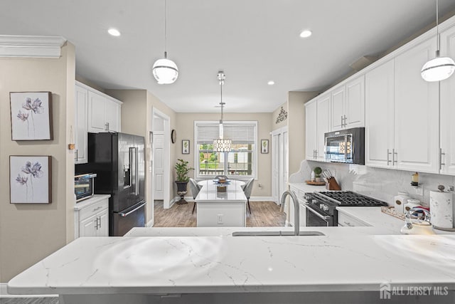 6 Traditions Pl, Monroe, NJ 08831 - kitchen with premium appliances, a center island, light wood-style floors, decorative backsplash, and light stone counters