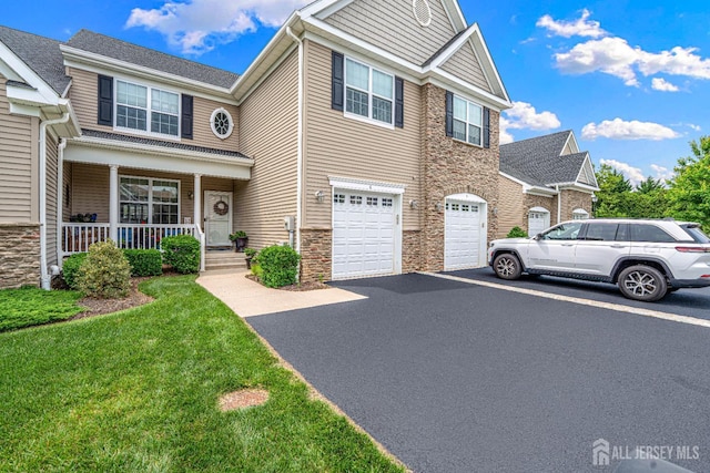 6 Traditions Pl, Monroe, NJ 08831 - view of front of house featuring driveway, a porch, an attached garage, stone siding, and a front lawn