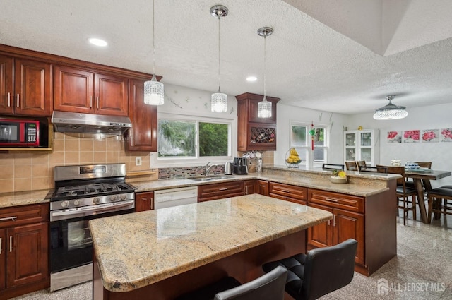 9 Merion Dr, Manalapan, NJ 07726 - kitchen with gas range, under cabinet range hood, a sink, a peninsula, and healthy amount of natural light
