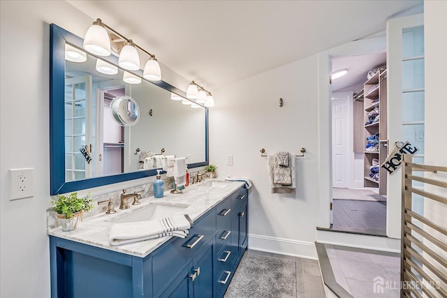 bathroom featuring baseboards, tile patterned floors, a sink, and double vanity
