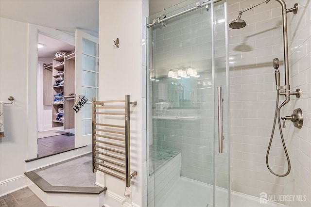 bathroom featuring a stall shower, radiator, and baseboards