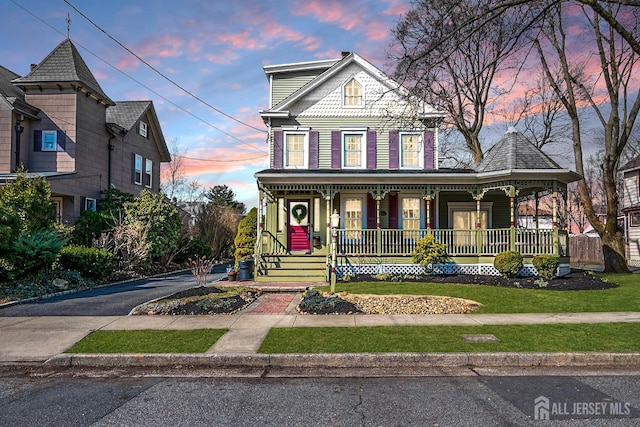 victorian-style house with a porch and a front lawn