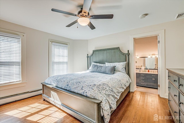 bedroom featuring light wood finished floors, visible vents, ensuite bath, a baseboard radiator, and ceiling fan