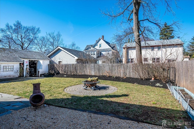 view of yard with an outdoor structure, a fenced backyard, and an outdoor fire pit