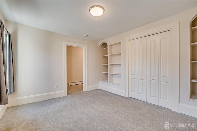 unfurnished bedroom with baseboards, a closet, carpet flooring, and baseboard heating