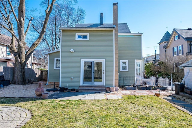 rear view of house featuring a patio, fence, a chimney, entry steps, and a lawn