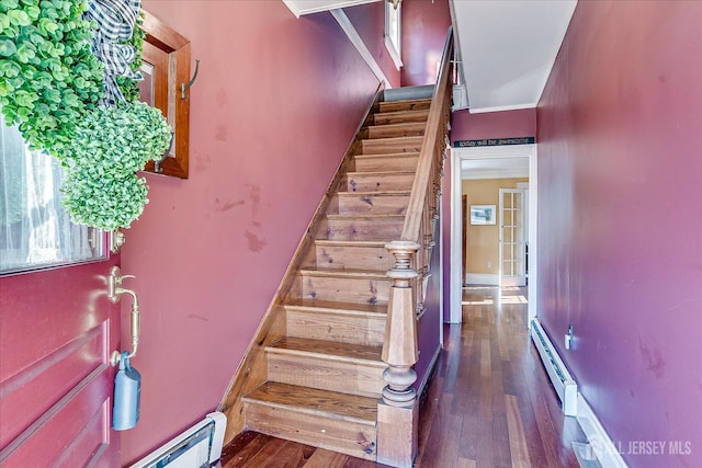 stairs with a baseboard heating unit, baseboards, and wood finished floors