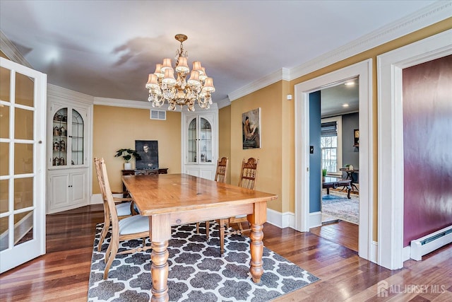 dining area featuring visible vents, ornamental molding, dark wood-type flooring, and a baseboard radiator