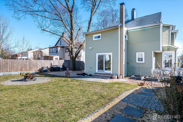 rear view of property featuring a fire pit, a chimney, fence, entry steps, and a yard
