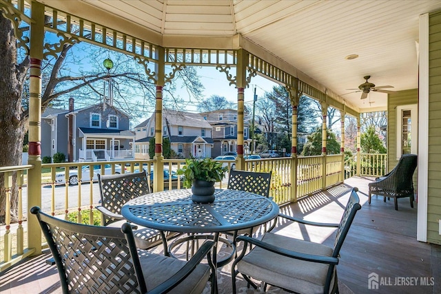 deck with ceiling fan, outdoor dining area, and a residential view