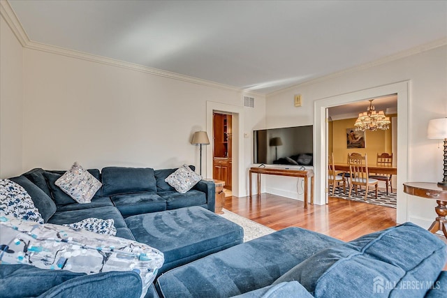 living room featuring an inviting chandelier, ornamental molding, wood finished floors, and visible vents