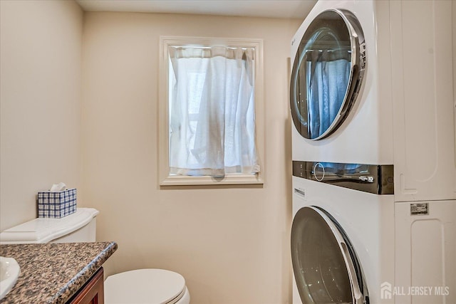 bathroom with toilet, vanity, and stacked washing maching and dryer