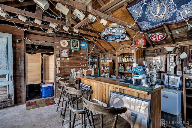 bar with a dry bar, concrete floors, and vaulted ceiling