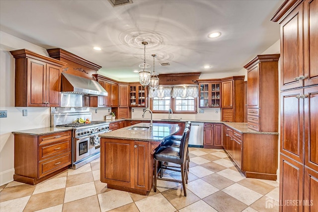 kitchen featuring wall chimney exhaust hood, brown cabinets, appliances with stainless steel finishes, and a sink