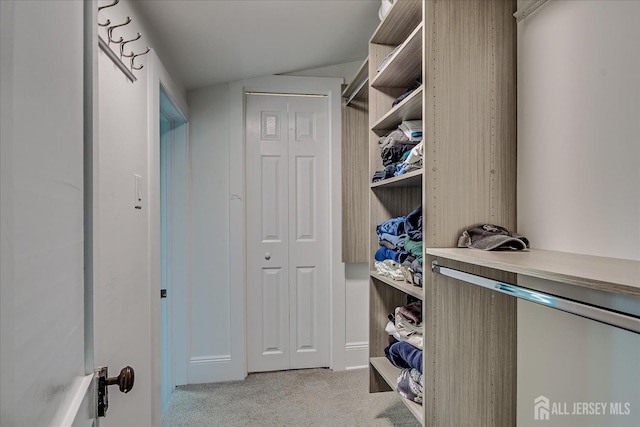 walk in closet with light carpet and lofted ceiling