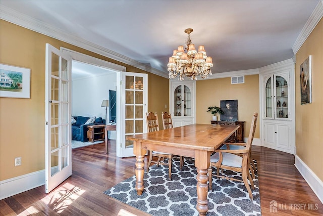 dining room with an inviting chandelier, crown molding, dark wood-style floors, and french doors