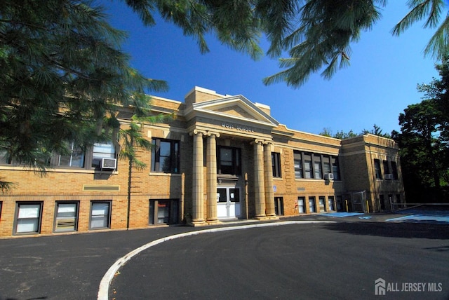 view of building exterior featuring cooling unit and uncovered parking