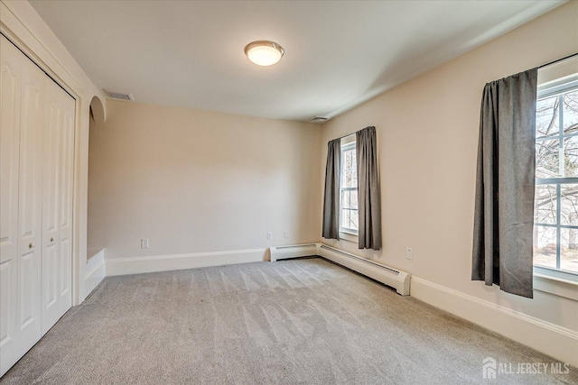 unfurnished bedroom with visible vents, multiple windows, carpet, and a baseboard radiator