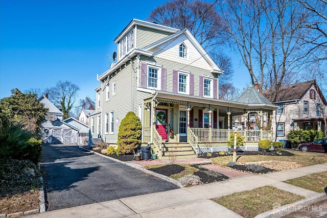 view of front facade featuring an outbuilding, covered porch, and a detached garage