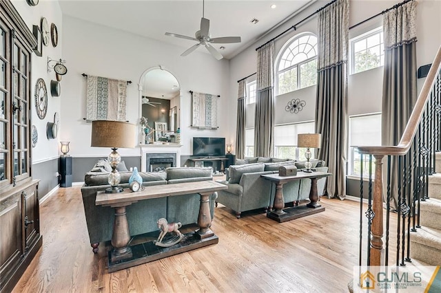 living room featuring light hardwood / wood-style flooring, ceiling fan, and a high ceiling