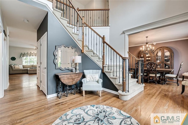 stairs featuring a chandelier, light wood-type flooring, and ornamental molding