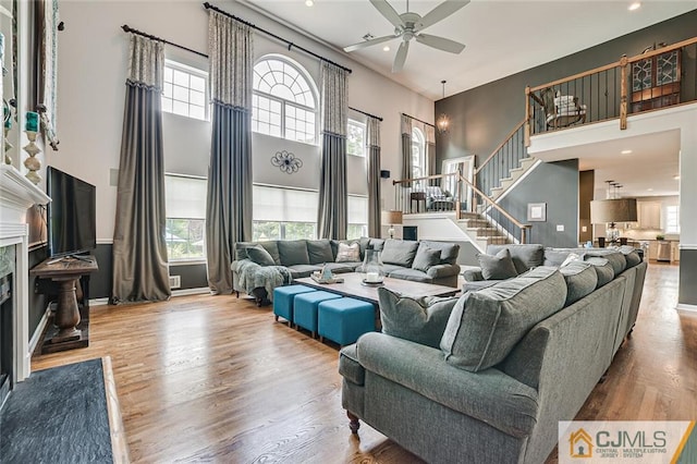 living room with hardwood / wood-style flooring, a towering ceiling, and ceiling fan