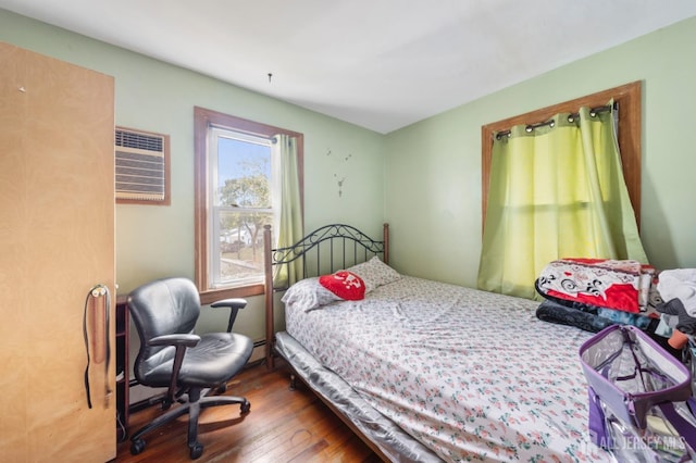 bedroom with hardwood / wood-style floors and an AC wall unit