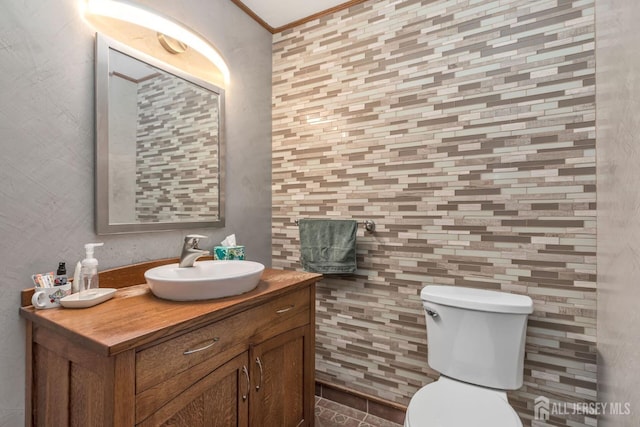 half bathroom with ornamental molding, toilet, and vanity