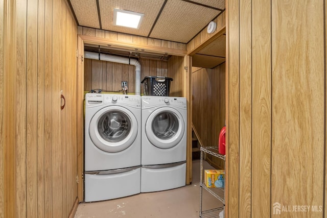 laundry area with wood walls, washer and dryer, and laundry area
