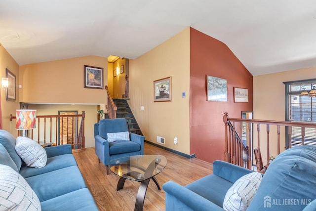 living room featuring baseboards, visible vents, light wood-type flooring, and vaulted ceiling