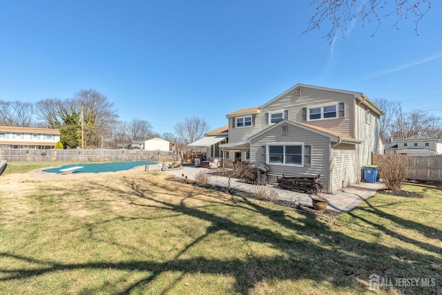 rear view of house with a fenced backyard, a fenced in pool, a patio, and a lawn