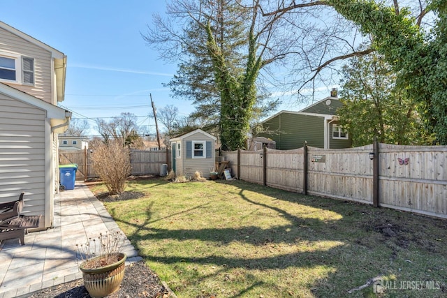 view of yard with an outbuilding, a fenced backyard, a shed, and a patio area