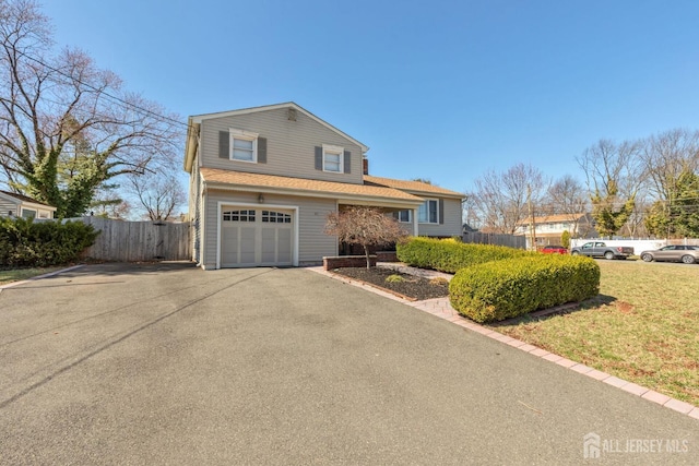 view of front of house featuring a garage, a front yard, fence, and aphalt driveway