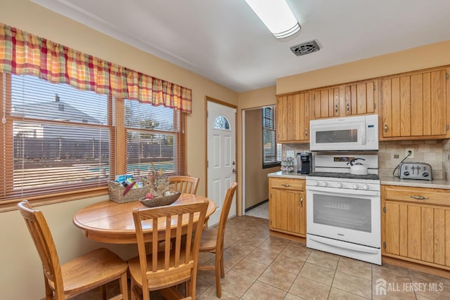 kitchen featuring visible vents, light countertops, white appliances, decorative backsplash, and light tile patterned flooring