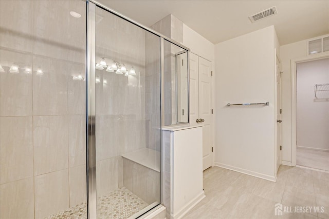 bathroom with a stall shower, a spacious closet, and visible vents