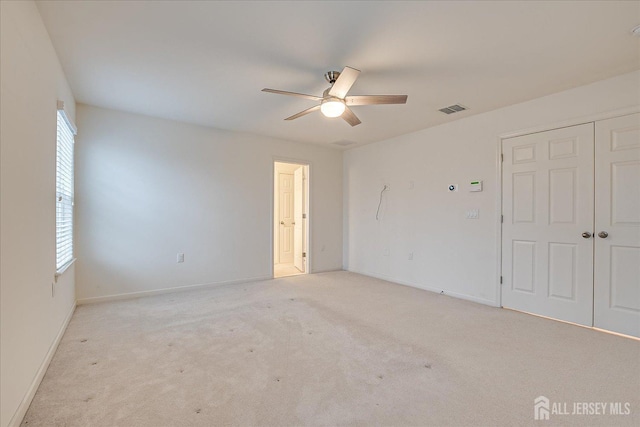 empty room with baseboards, a ceiling fan, visible vents, and light colored carpet