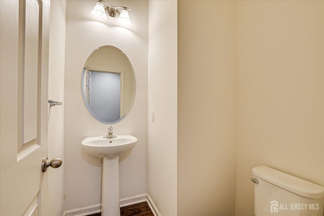 half bathroom featuring baseboards and toilet