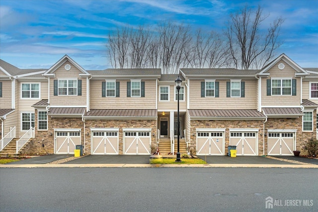 townhome / multi-family property featuring driveway, stone siding, metal roof, and a standing seam roof