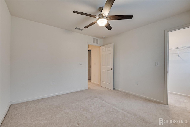 unfurnished bedroom with light carpet, baseboards, visible vents, and a walk in closet