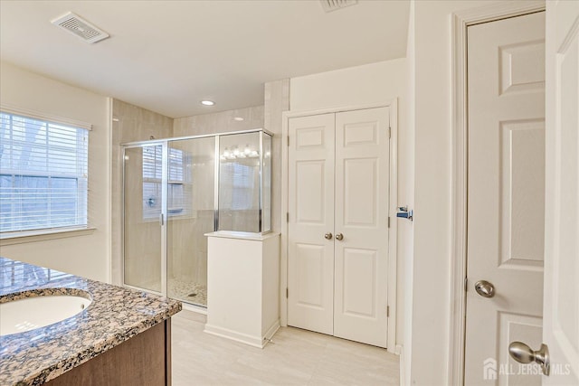 bathroom featuring vanity, a closet, a shower stall, and visible vents