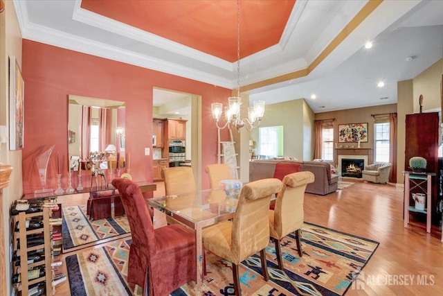 56 Kings Mill Rd, Monroe, NJ 08831 - dining area with a tray ceiling, a chandelier, light wood-style floors, ornamental molding, and a lit fireplace
