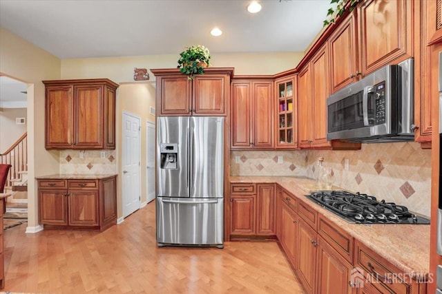 56 Kings Mill Rd, Monroe, NJ 08831 - kitchen with stainless steel appliances, brown cabinets, light stone counters, tasteful backsplash, and light wood-type flooring