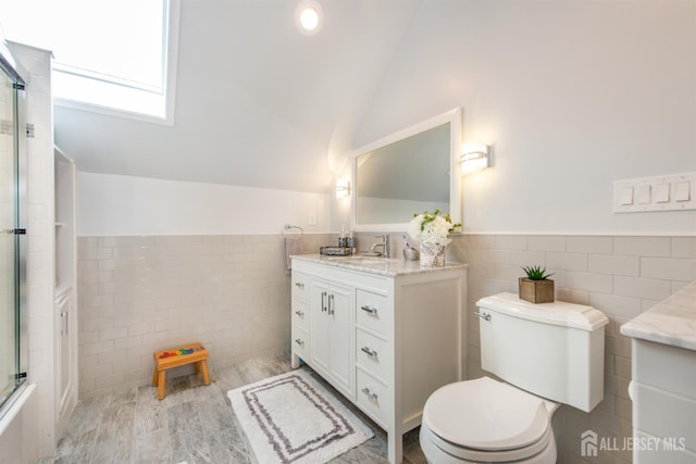 13 Clinton Ave, Edison, NJ 08820 - full bathroom featuring tile walls, vanity, vaulted ceiling, toilet, and a wainscoted wall