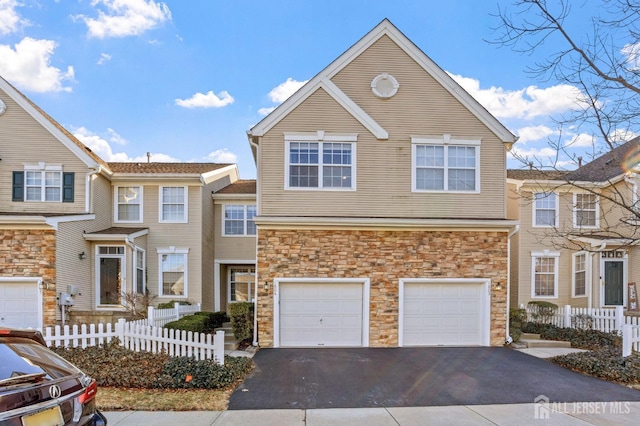 view of front of house with a garage, driveway, and fence