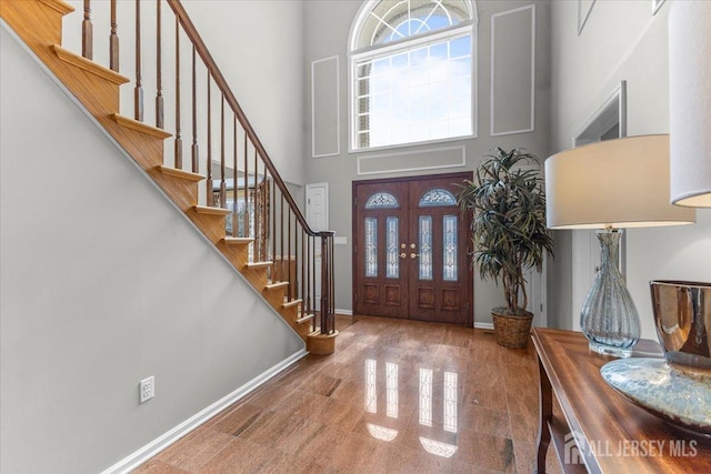 foyer entrance featuring stairs, granite finish floor, baseboards, and a towering ceiling