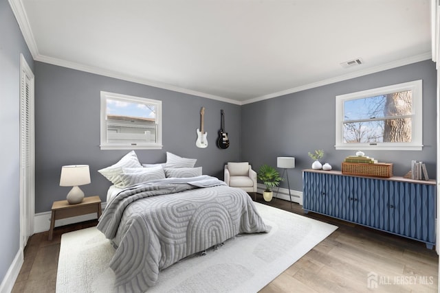 bedroom featuring crown molding, wood finished floors, and visible vents