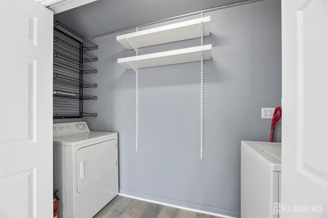 clothes washing area featuring washing machine and clothes dryer, wood finished floors, and laundry area